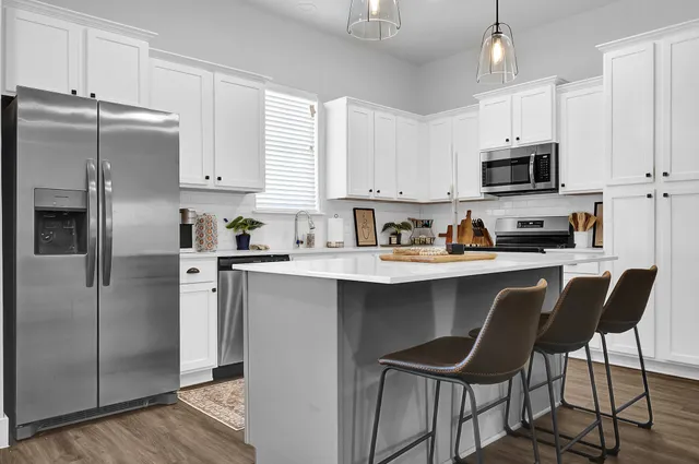 a kitchen with stainless steel appliances granite countertop a refrigerator a sink a stove a microwave and wooden cabinets