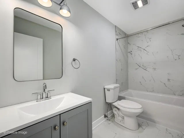a bathroom with a toilet sink a mirror and shower