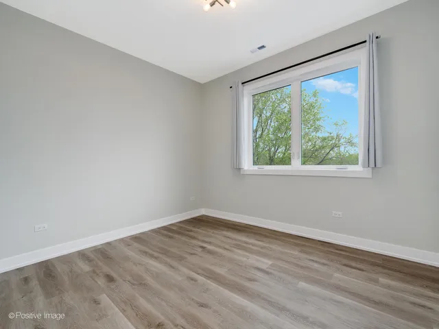 a view of a big room with wooden floor and windows