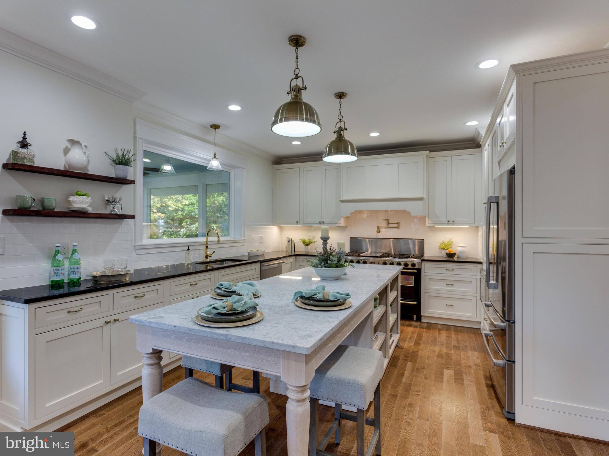3722 Chesapeake Street Northwest Washington, DC 20016 - Photo 8 of 30 a kitchen with stainless steel appliances a stove a sink a kitchen island with chairs and wooden floor