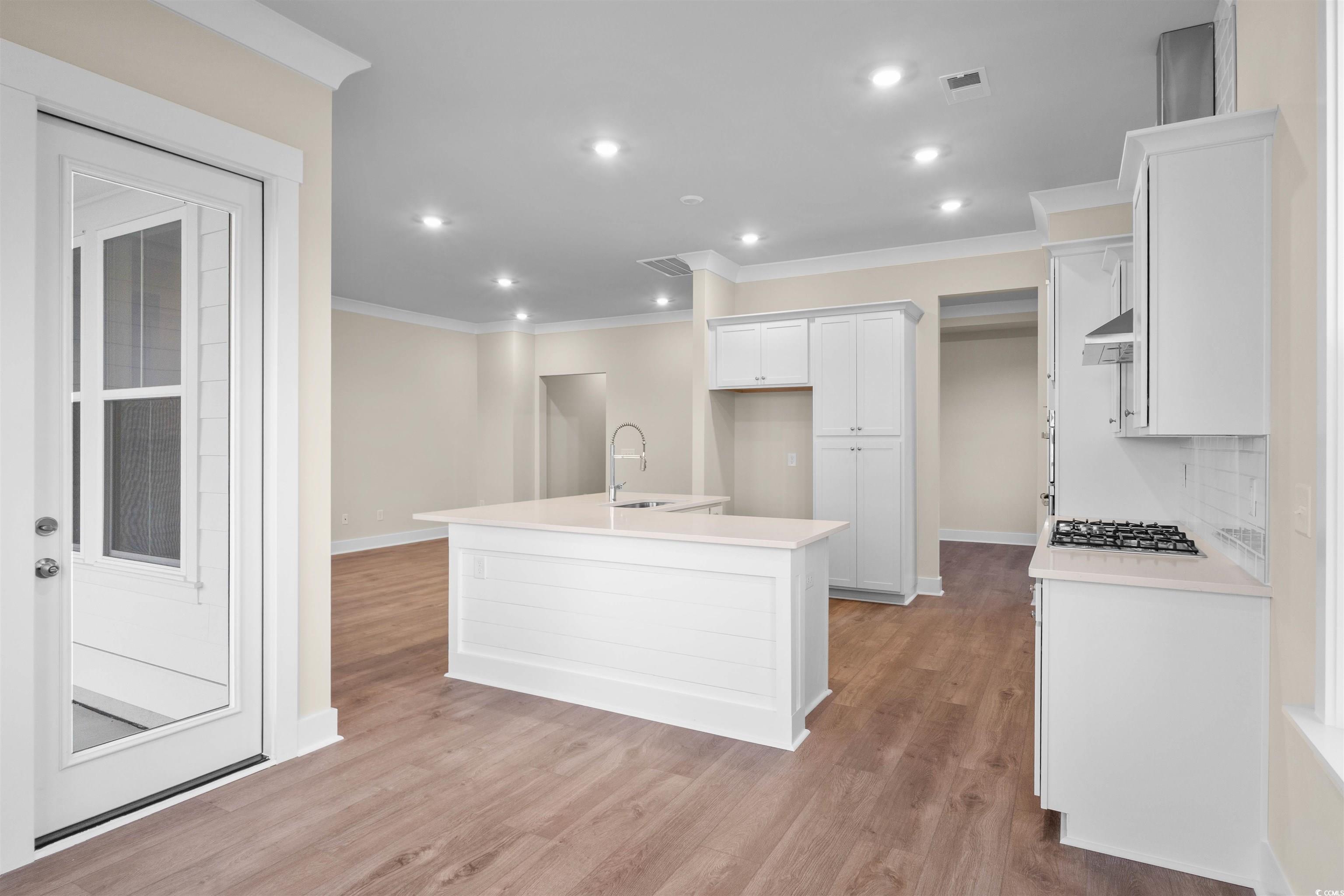 224 Atlantic Breeze Street Myrtle Beach, SC 29572 - Photo 16 of 39 Kitchen with an island with sink, white cabinetry, ornamental molding, recessed lighting, and light wood finished floors