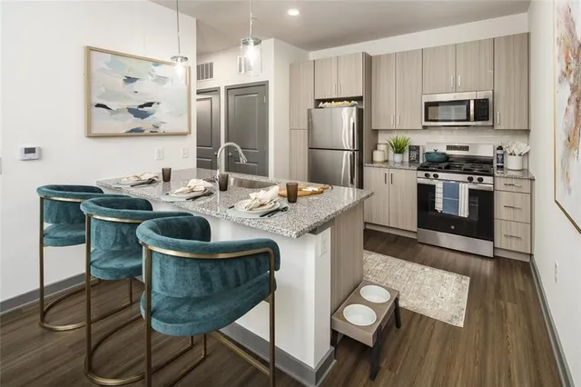 a kitchen with stainless steel appliances granite countertop a stove a refrigerator a microwave a sink and white cabinets