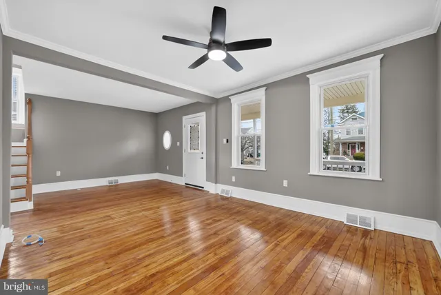 a view of empty room with wooden floor and fan