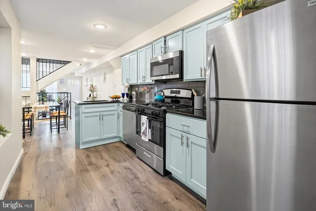 a kitchen with stainless steel appliances a refrigerator a stove a sink cabinets and a dining table