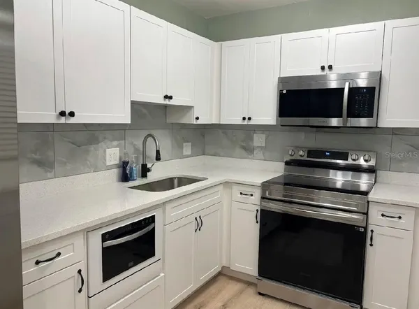 a kitchen with granite countertop white cabinets and stainless steel appliances
