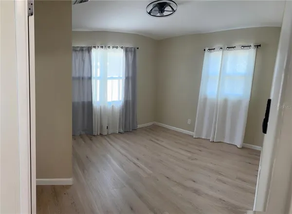 an empty room with wooden floor and windows