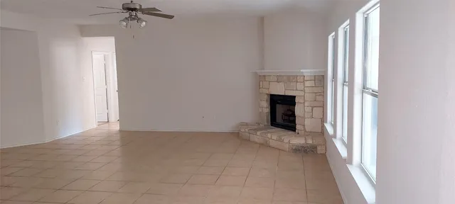 an empty room with windows and fireplace