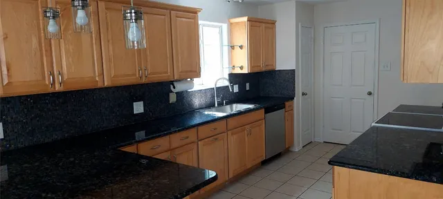 a kitchen with granite countertop white cabinets and black appliances