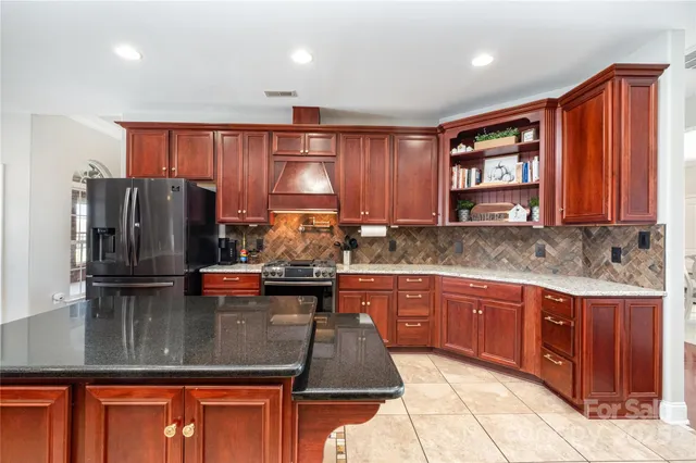 a kitchen with stainless steel appliances granite countertop a refrigerator a sink dishwasher a stove with wooden cabinets and floor