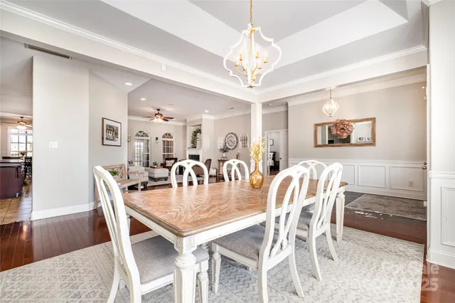 a dining room with wooden floor a chandelier a wooden table and chairs