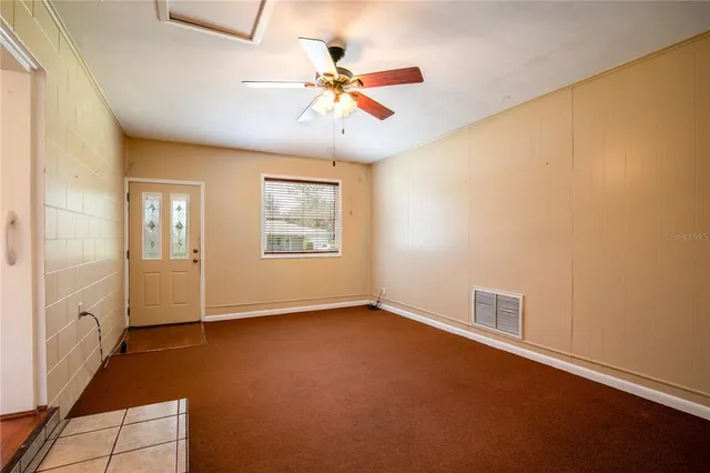 an empty room with windows and fan