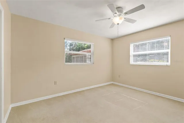an empty room with a window and a ceiling fan