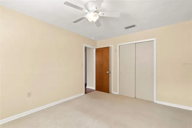an empty room with closet and a chandelier fan