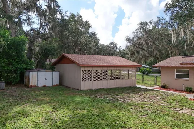 a view of a house with a yard and large tree
