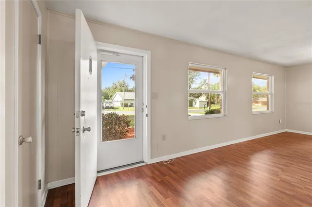 a view of an empty room with wooden floor and a window