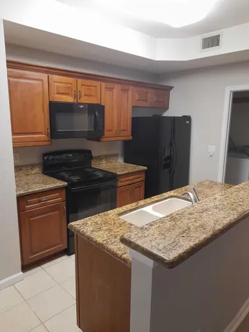 a kitchen with granite countertop a refrigerator and a sink