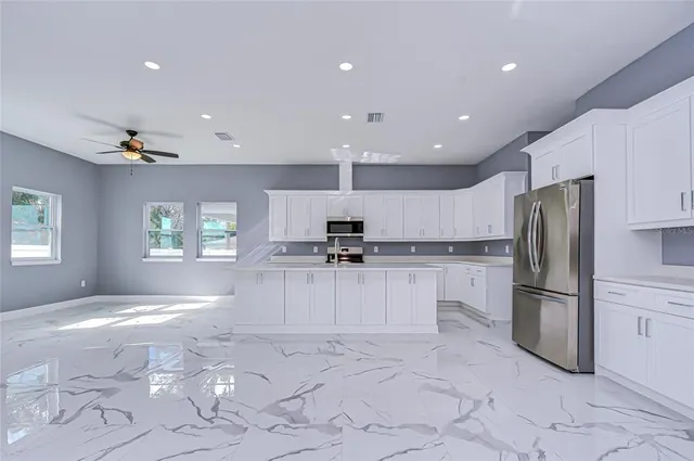 a kitchen with white cabinets a refrigerator and a stove top oven