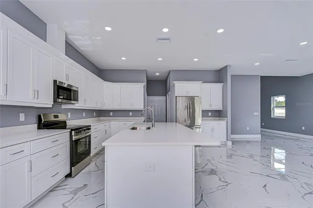 a kitchen with a sink stainless steel appliances and white cabinets