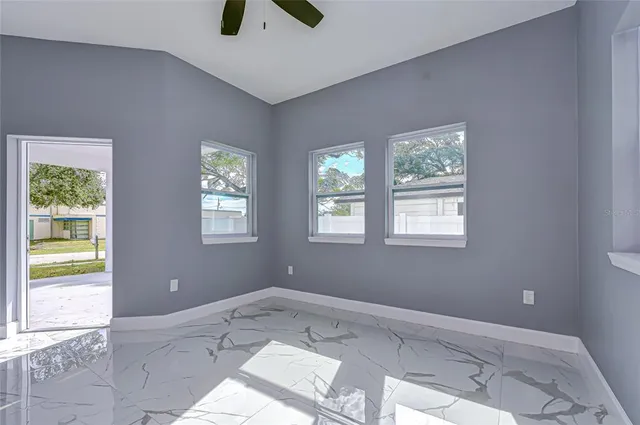 a view of an empty room with window and hardwood floor