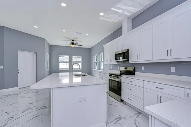 a kitchen with granite countertop white cabinets stainless steel appliances and a counter top space