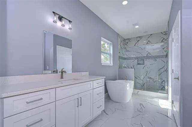 a spacious bathroom with a granite countertop sink a toilet a mirror and shower
