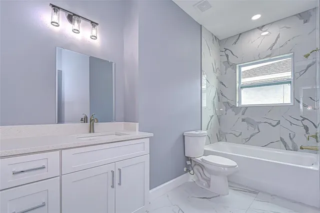 a bathroom with a sink toilet vanity and tub