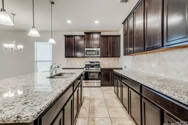 a kitchen with granite countertop stainless steel appliances a sink stove top oven and cabinets