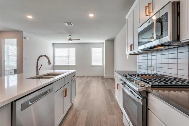 a kitchen with stainless steel appliances a sink stove and cabinets