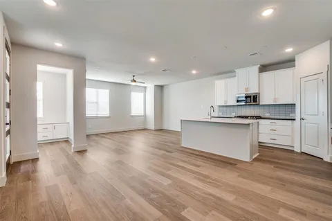 a large kitchen with stainless steel appliances granite countertop a stove a sink and white cabinets with wooden floor