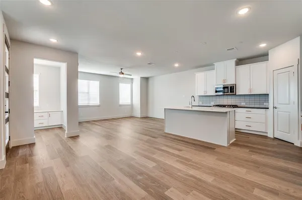 a large kitchen with stainless steel appliances granite countertop a stove a sink and white cabinets with wooden floor