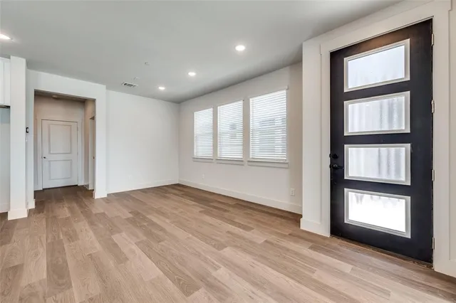 a view of an empty room with window and wooden floor