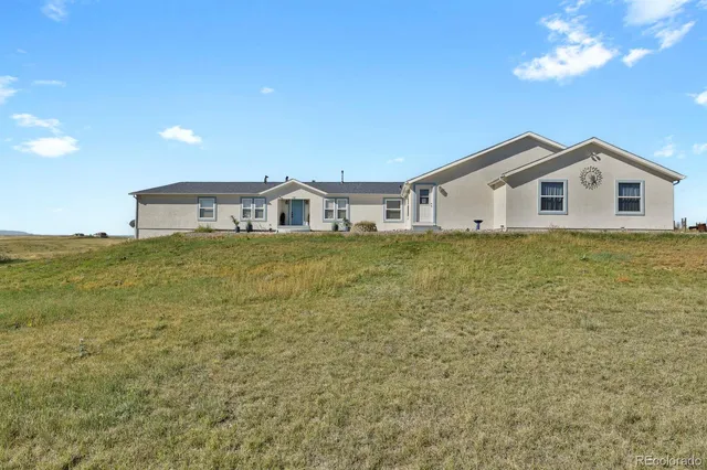 a view of a house with a big yard and large trees