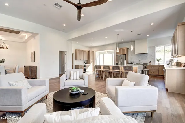a large white kitchen with a large island in the center a sink stainless steel appliances and cabinets