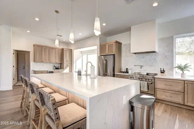 a living room with stainless steel appliances kitchen island granite countertop a table chairs and a sink