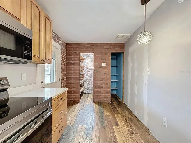 an empty room with a chandelier fan and windows