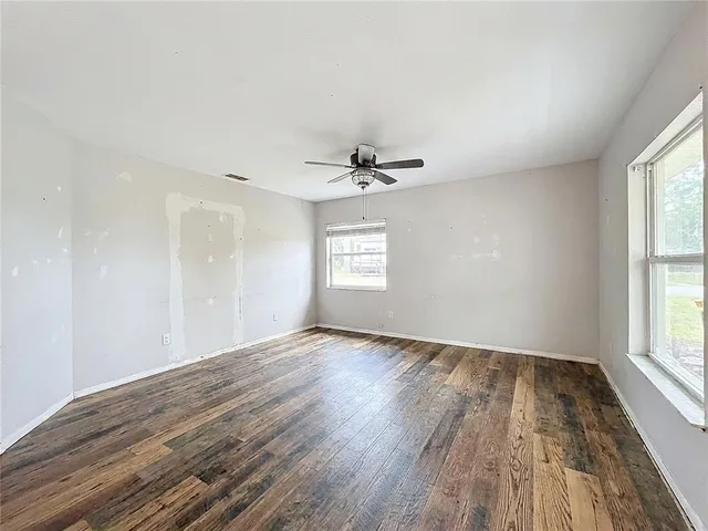 a view of empty room with wooden floor and ceiling fan