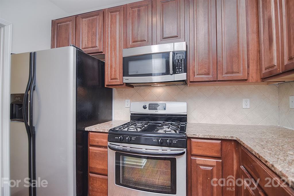610 Raphael Place Charlotte, NC 28205 - Photo 6 of 27 a kitchen with granite countertop a stove and a microwave with cabinets