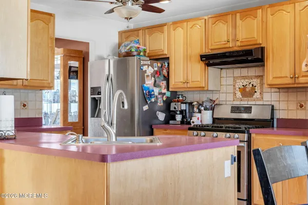 a kitchen with stainless steel appliances kitchen island granite countertop a refrigerator and a stove top oven