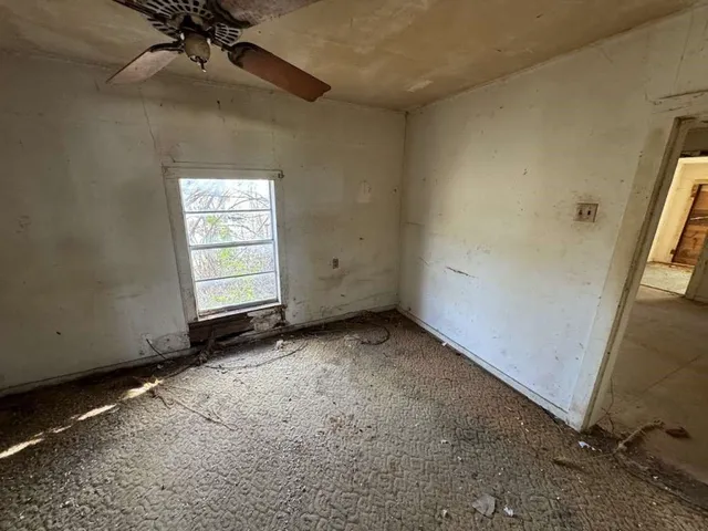 an empty room with a ceiling fan and window