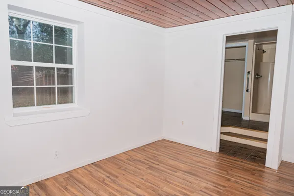 an empty room with wooden floor and windows
