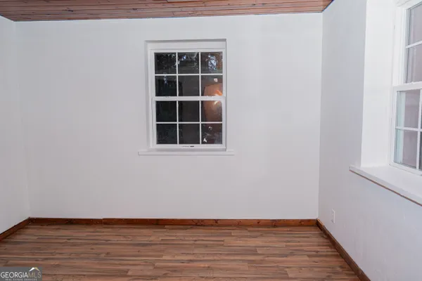 a view of an empty room with wooden floor and windows