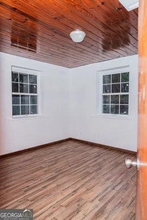 a view of an empty room with wooden floor and windows