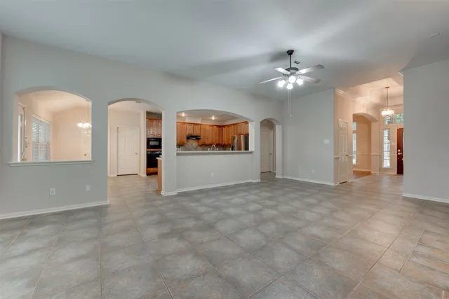 an empty room with fan and way to kitchen