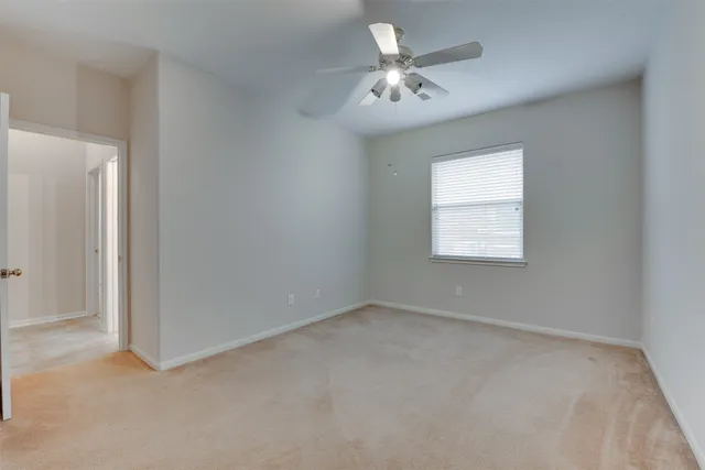 an empty room with a chandelier fan and windows