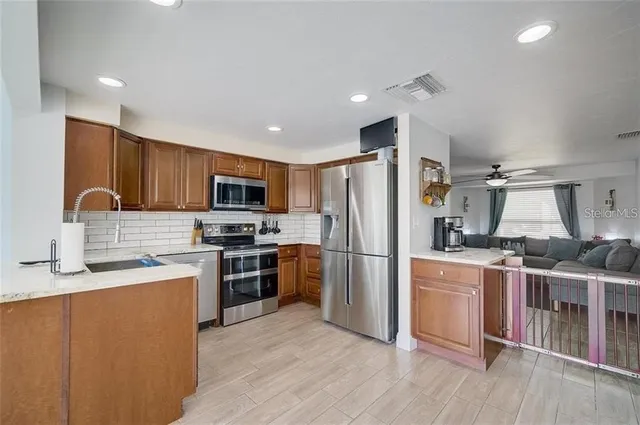 a kitchen with stainless steel appliances granite countertop a stove top oven a refrigerator a sink and dishwasher with wooden floor