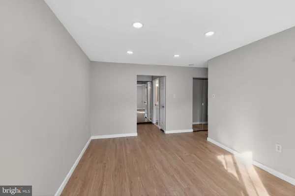 a view of an empty room with wooden floor and closet