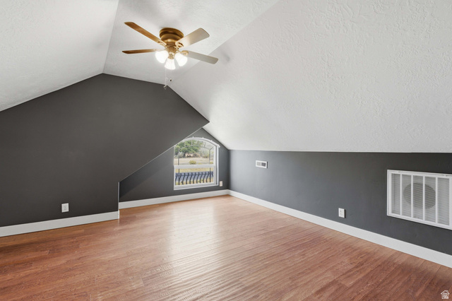 2567 West Rim Rock Drive Stockton, UT 84071 - Photo 36 of 64 Sloped ceiling room featuring wood-finish flooring, a ceiling fan, and an arched window