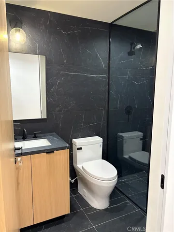 a white toilet sitting next to a bathroom sink and a shower