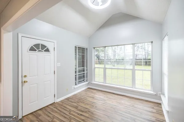 an empty room with wooden floor and windows