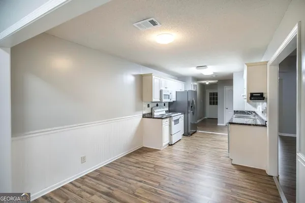 a large kitchen with a center island wooden floor and stainless steel appliances